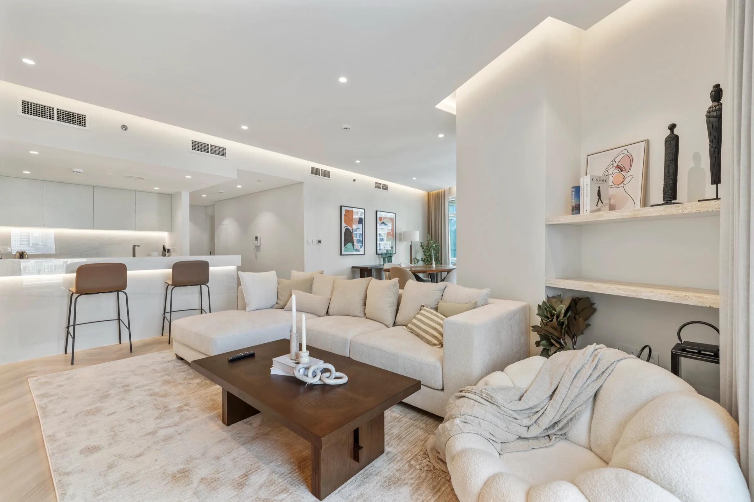 A bright open-plan living space with a cream sofa and built-in shelving