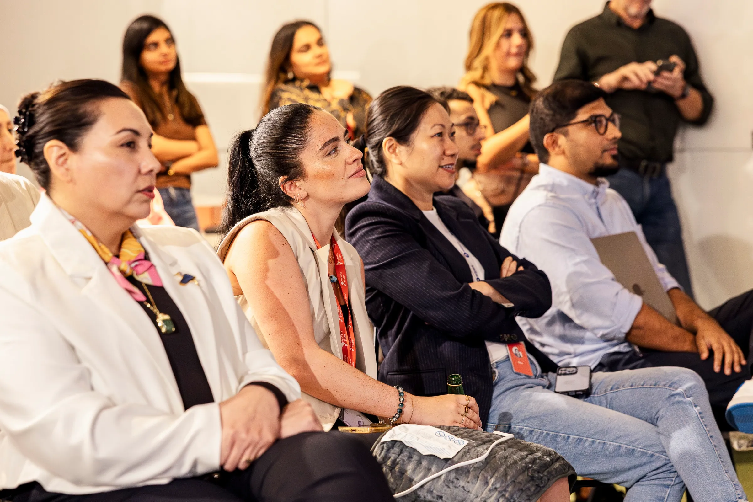 An audience seated closely together listening during a filmed panel session