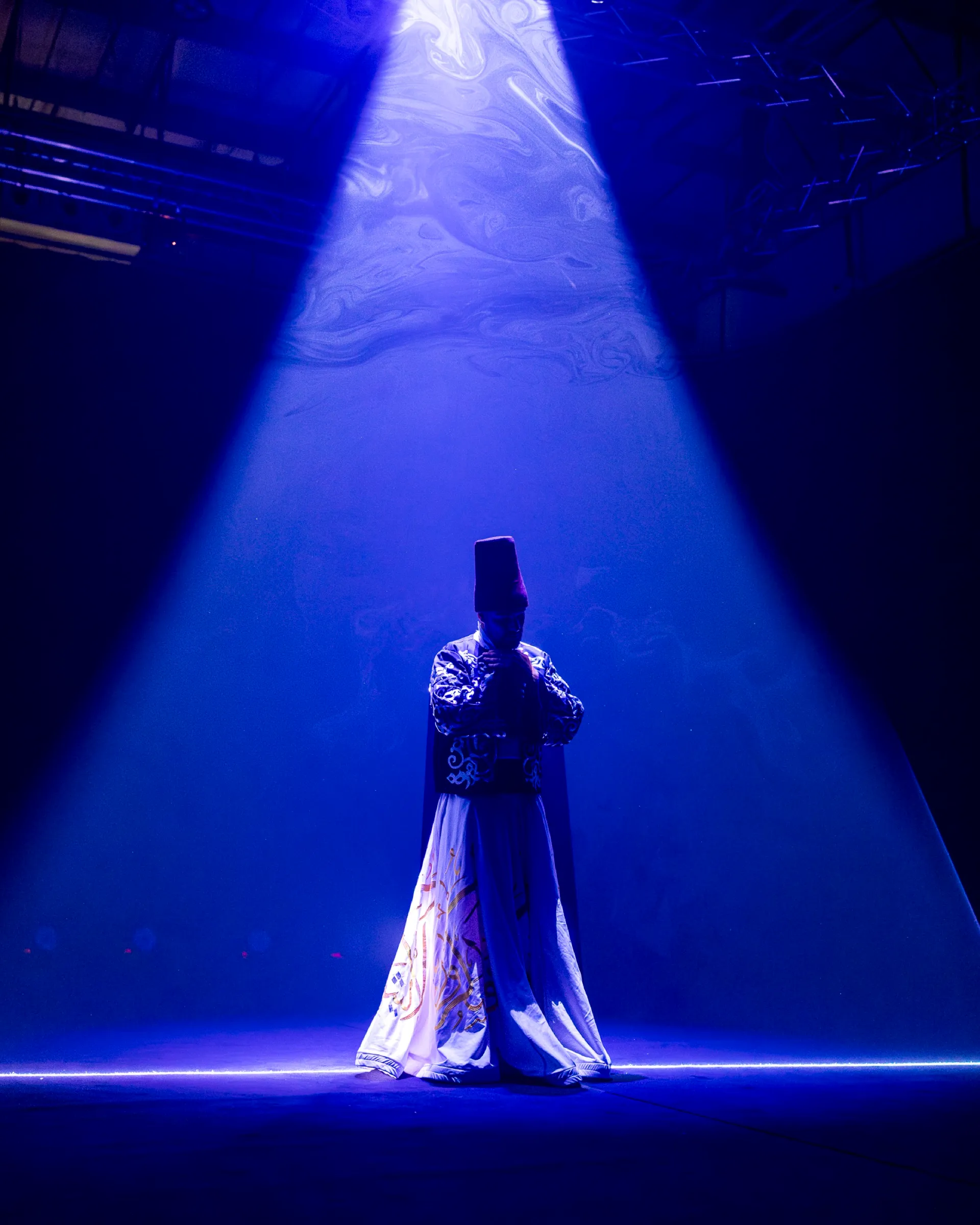 A solo dancer lit by a single blue spotlight on a darkened stage