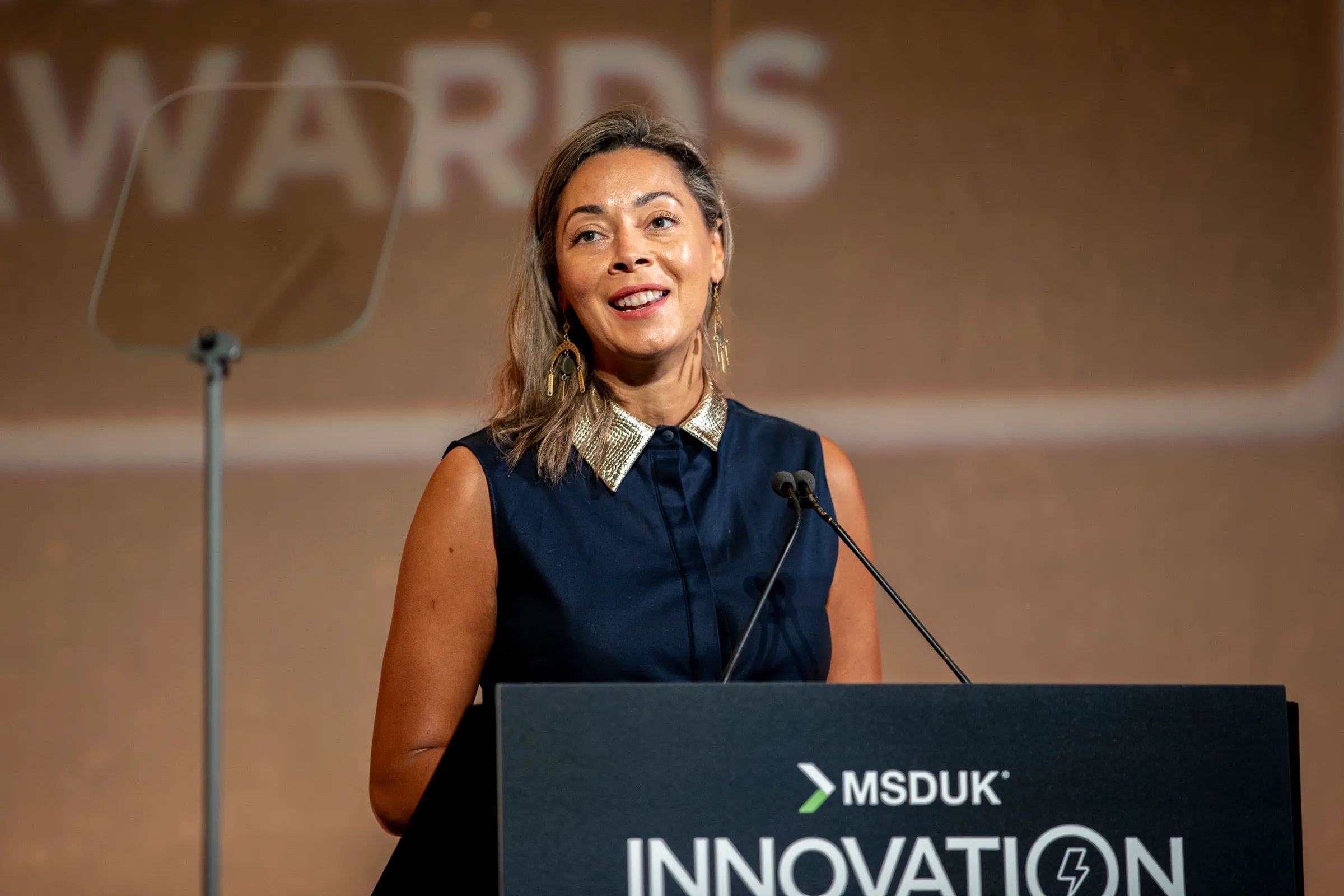 A speaker addressing delegates from a branded podium at an innovation conference