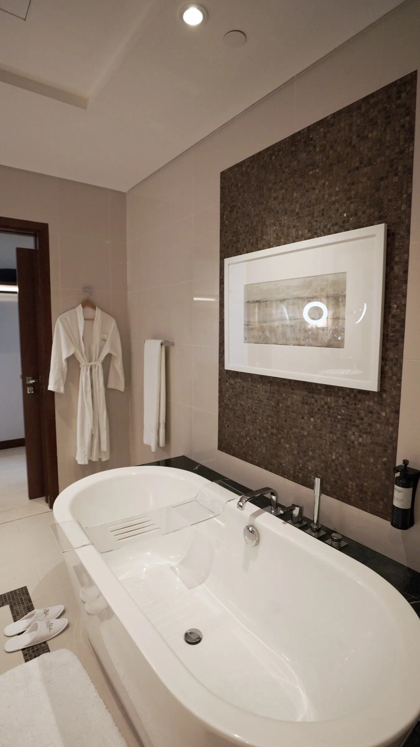 A marble bathroom suite with a freestanding bath and framed artwork