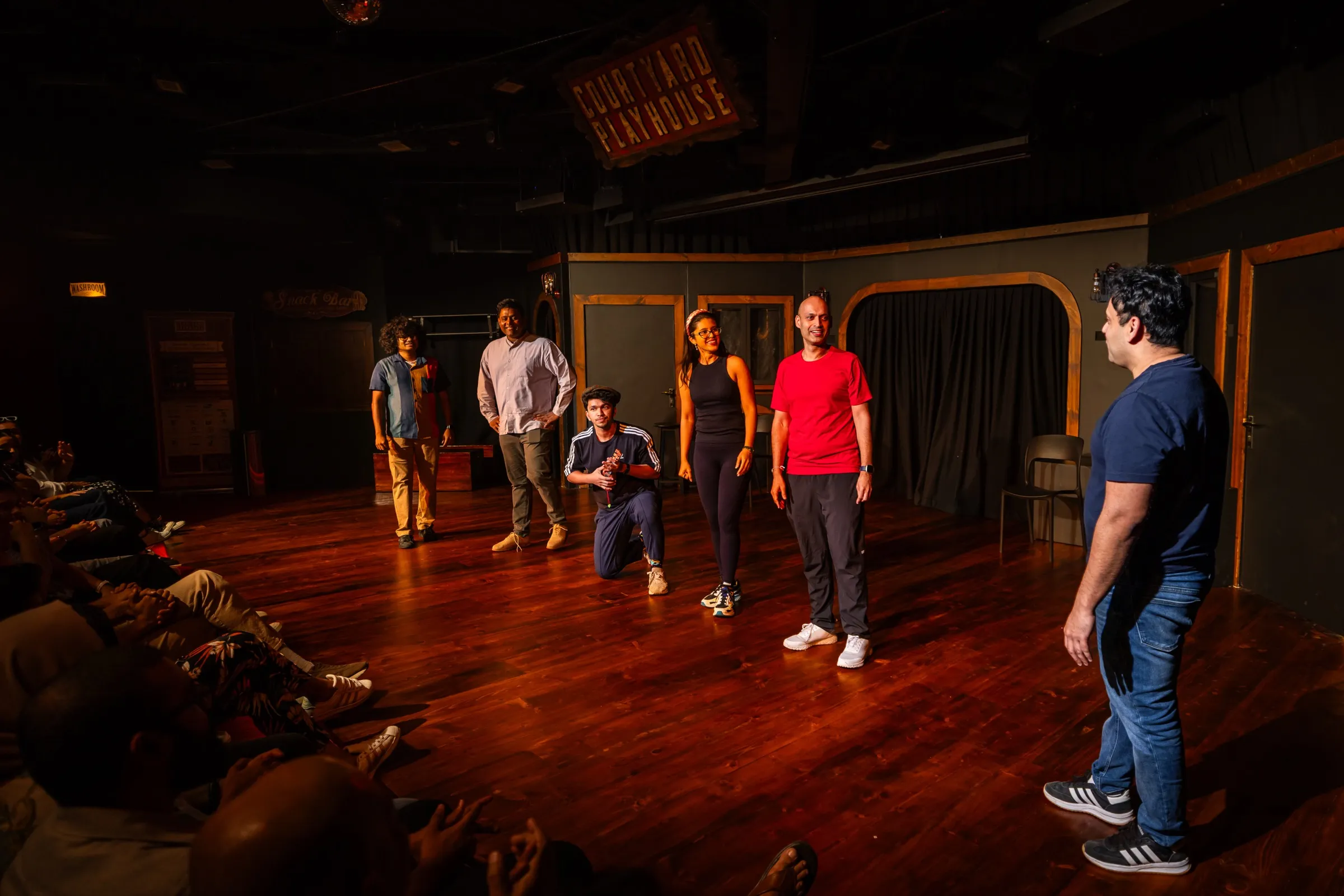 A theatre ensemble performing together on a wooden stage during a live show