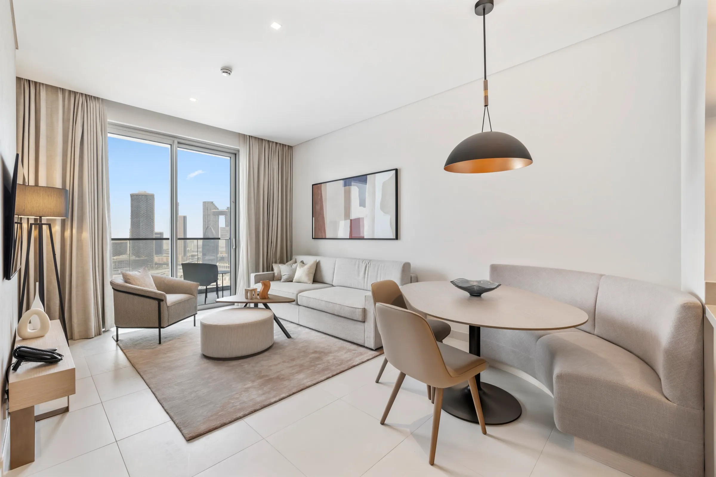 A bright residence living and dining space with a pendant light and city skyline through the window